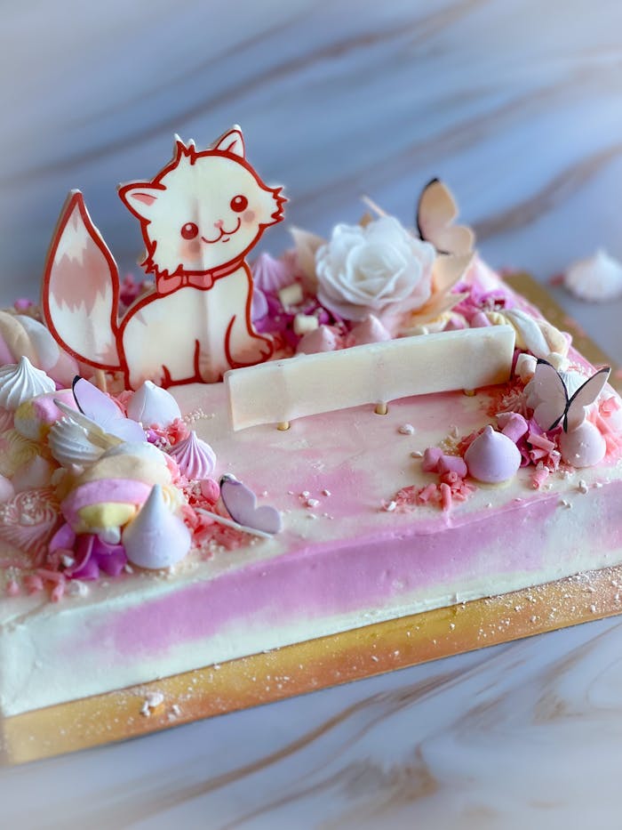 Adorable cat-themed cake with pink and white decorations, perfect for celebrations.