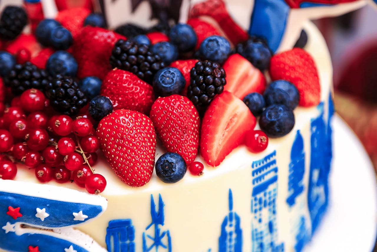 Close-up of a berry-topped cake with red, white, and blue decorations, celebrating patriotism.